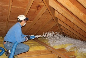 Technician installing blown-in attic insulation.