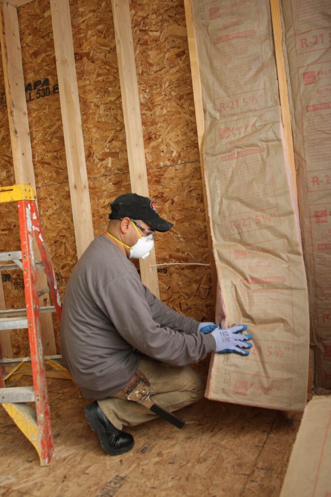 Insulation contractor installing fiberglass batt insulation in a wall